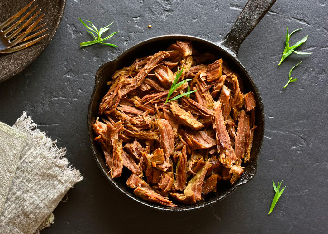 des morceau de viande d'agneau effilochés dans une poêle en fonte